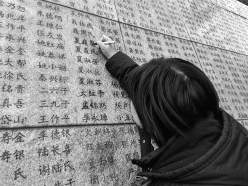 南京大屠杀幸存者夏淑琴的外孙女夏媛为“哭墙”上家人的姓名“描新”新华社发
